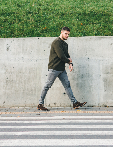 man in sweater walking by sidewalk