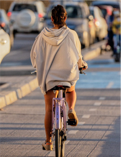young latin woman on a bicycle on a bikeway at beautiful sunset